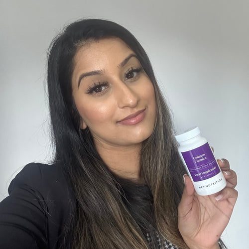 Woman holding a bottle of Hey Nutrition Collagen Complex food supplement with hyaluronic acid and sea kelp, 60 capsules, smiling at the camera.