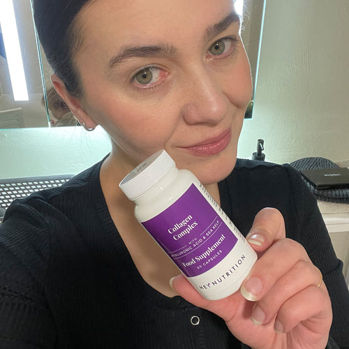 Woman indoors holding a bottle of Hey Nutrition Collagen Complex food supplement with hyaluronic acid and sea kelp, 60 capsules, close to her face.