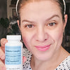 Woman smiling slightly while holding a bottle of Hey Nutrition Probiotic Complex.