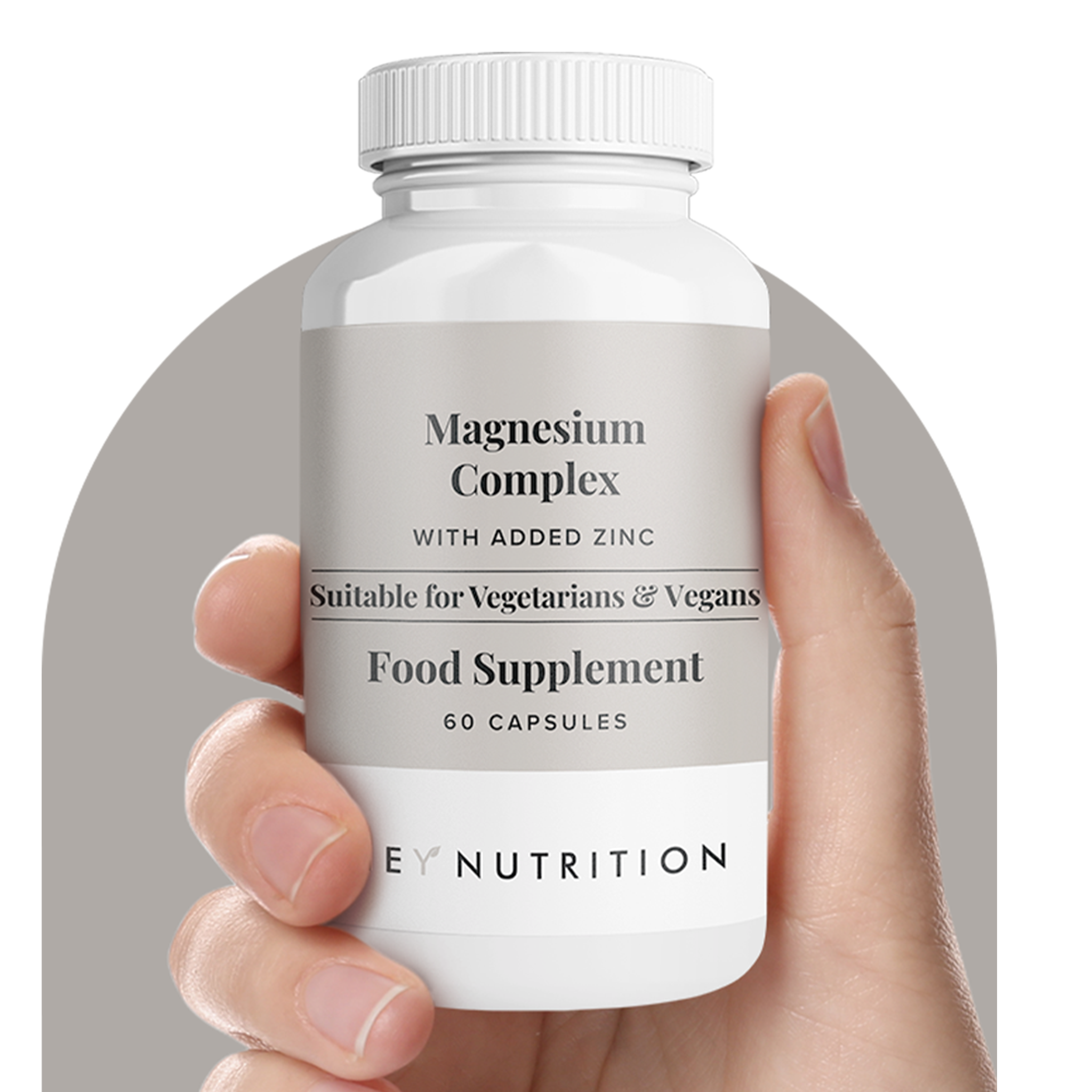 A hand holding a bottle of Hey Nutrition Magnesium Complex food supplement, 60 capsules, with a grey circular background. Label highlights “With Added Zinc” and “Suitable for Vegetarians & Vegans.”