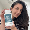 Lady with dark hair smiling while holding a bottle of Thyroid Complex.
