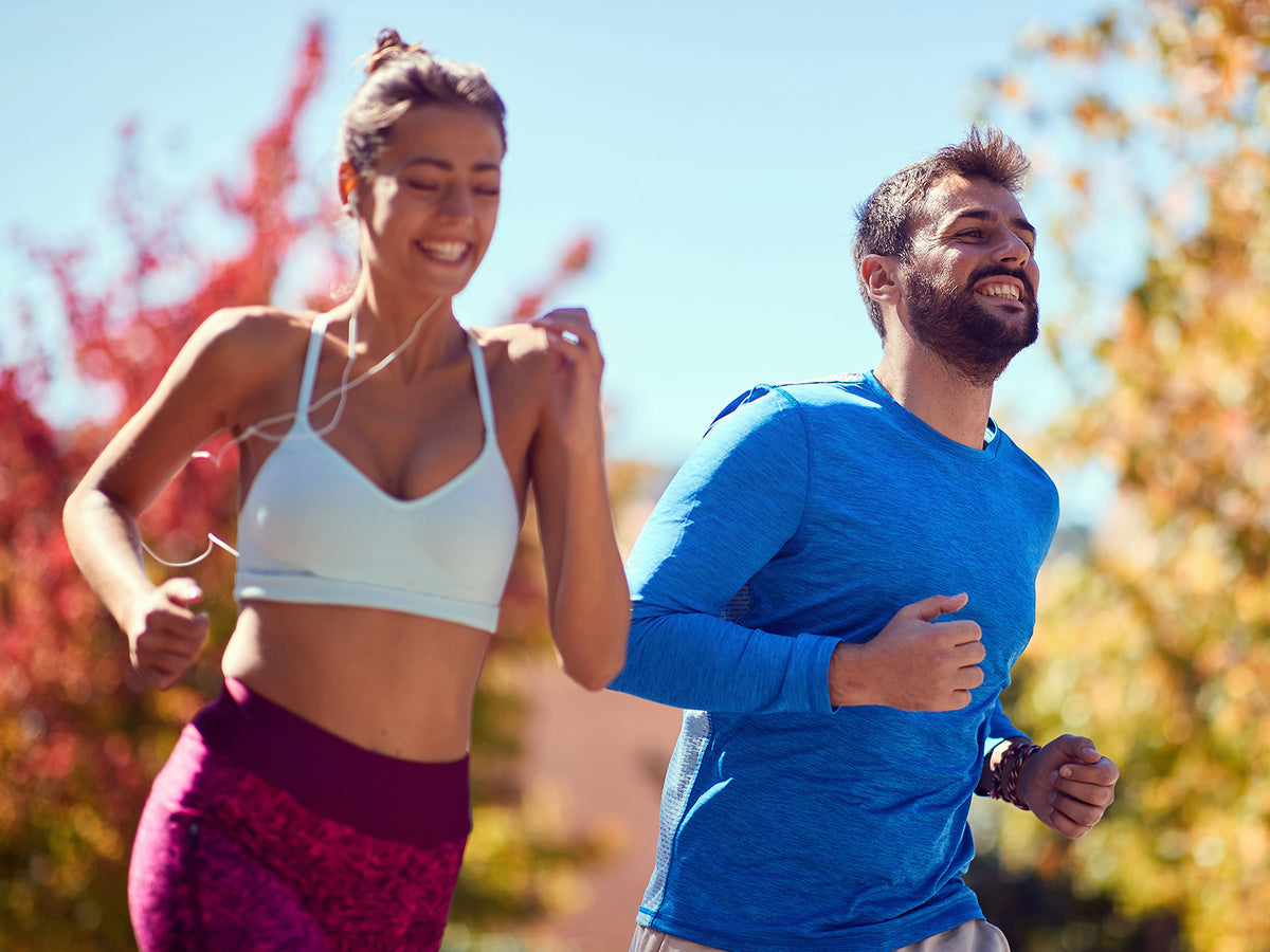 "Smiling couple jogging outdoors in sportswear, symbolizing energy, stamina, and healthy lifestyle supported by multivitamins and minerals."